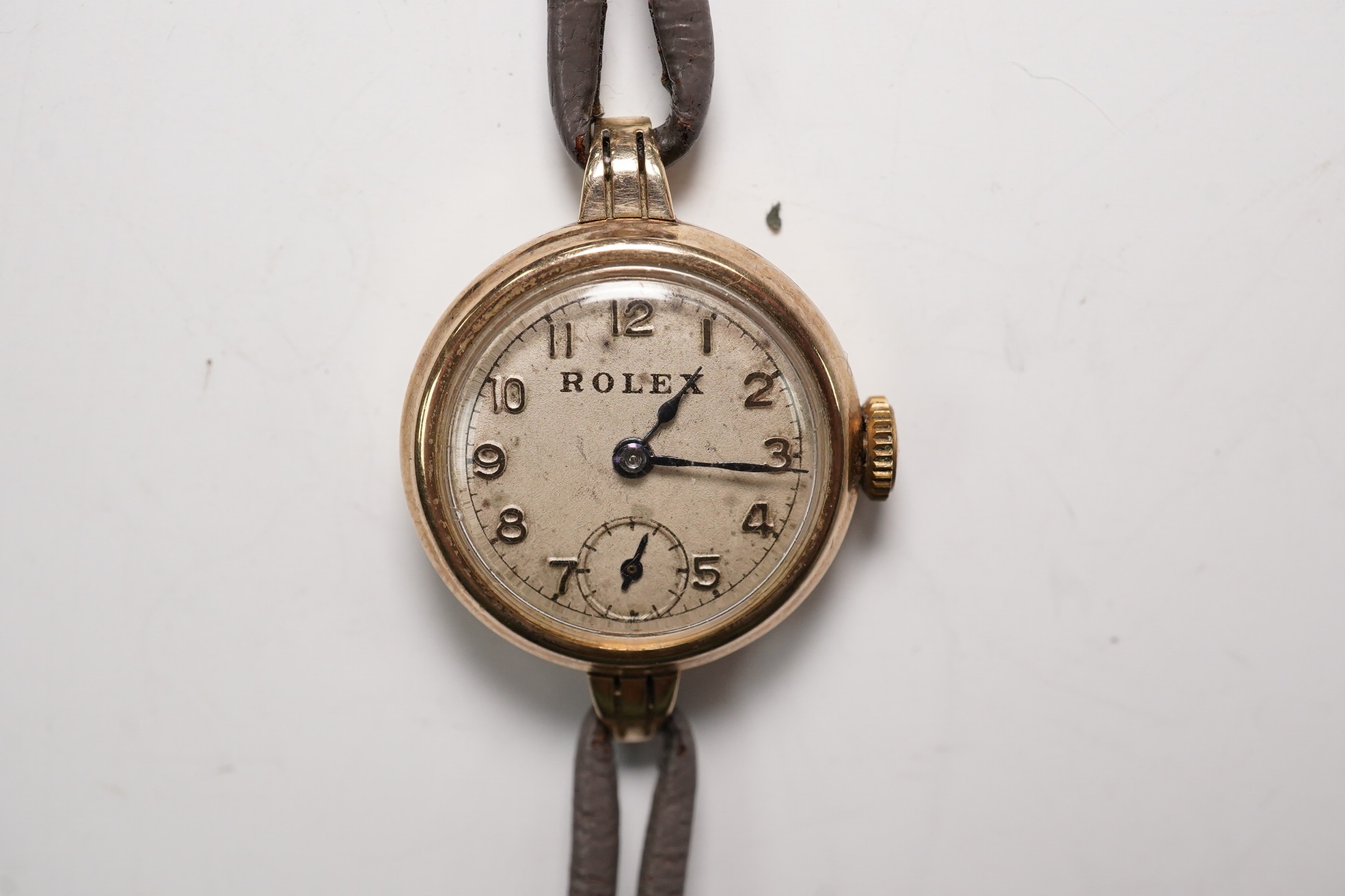 A lady's 9ct gold Rolex manual wind wrist watch, with Arabic dial and subsidiary seconds, case back numbered 22110, case diameter 21mm, on an associated twin strand fabric strap. Condition - poor to fair